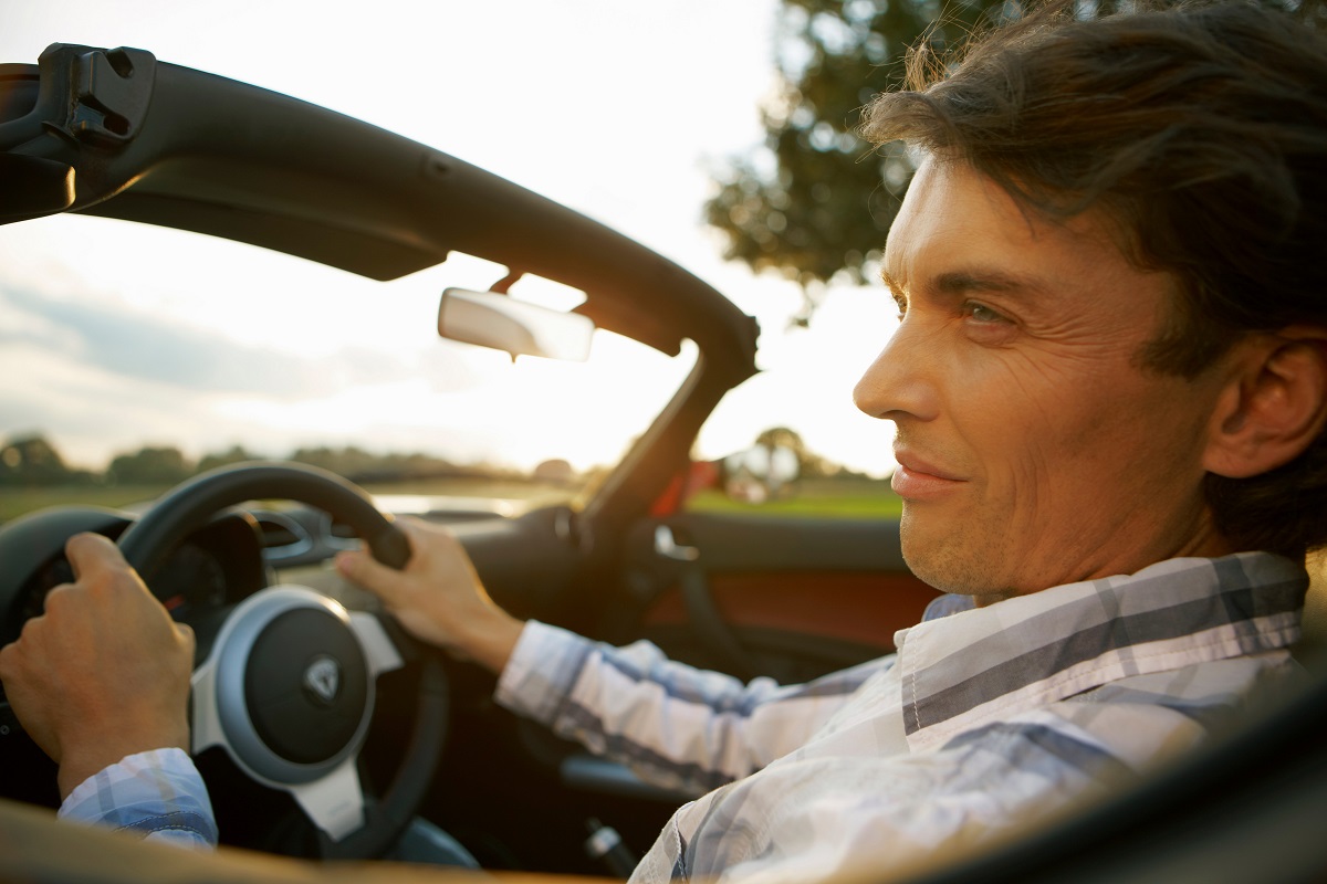 man smiling while driving a car